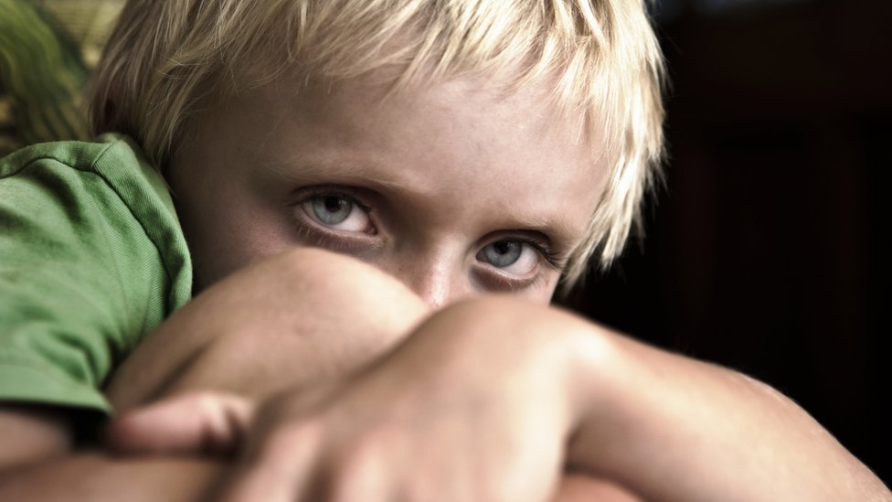 Файловая фотография мальчика-блондинки с голубыми глазами, съежившимися
