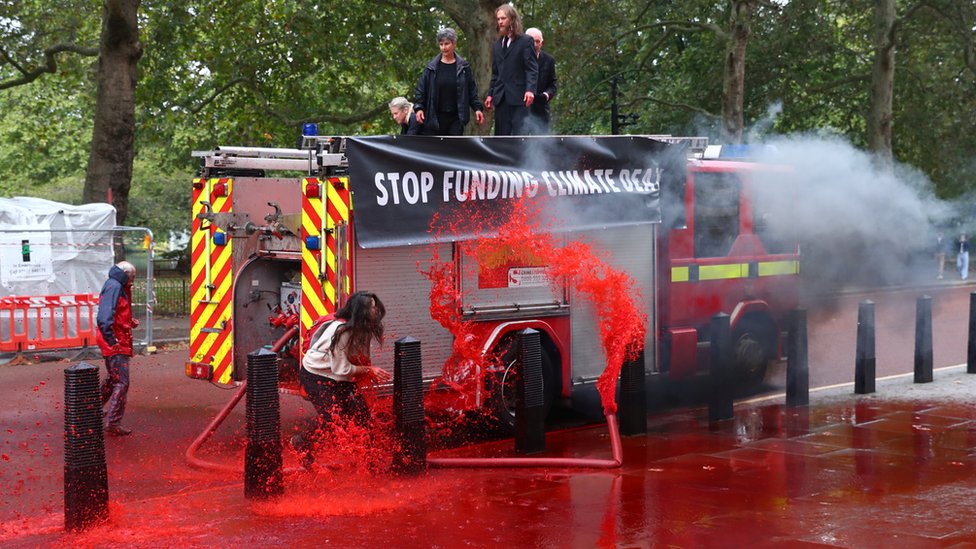 Протестующие восстания вымирания брызгают красной водой на казначейство