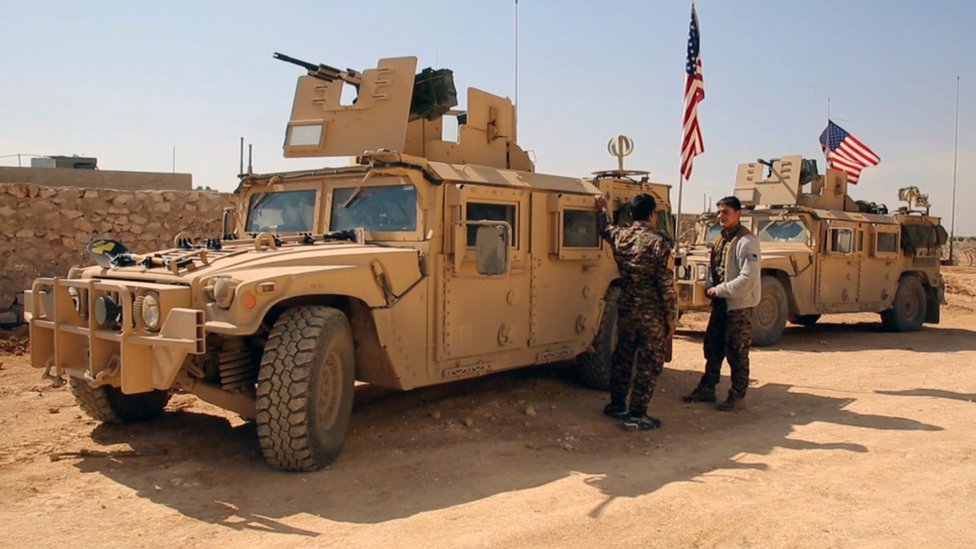 Боевики Сирийских демократических сил стоят возле военной техники США на окраине сирийского города Манбидж (7 марта 2017 г.)
