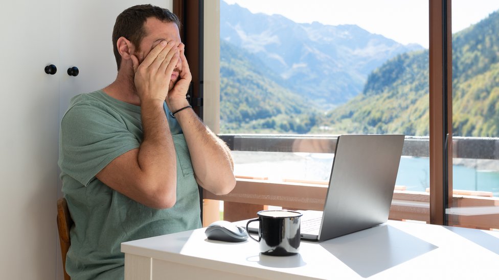 Un hombre se muestra agotado frente a su laptop.