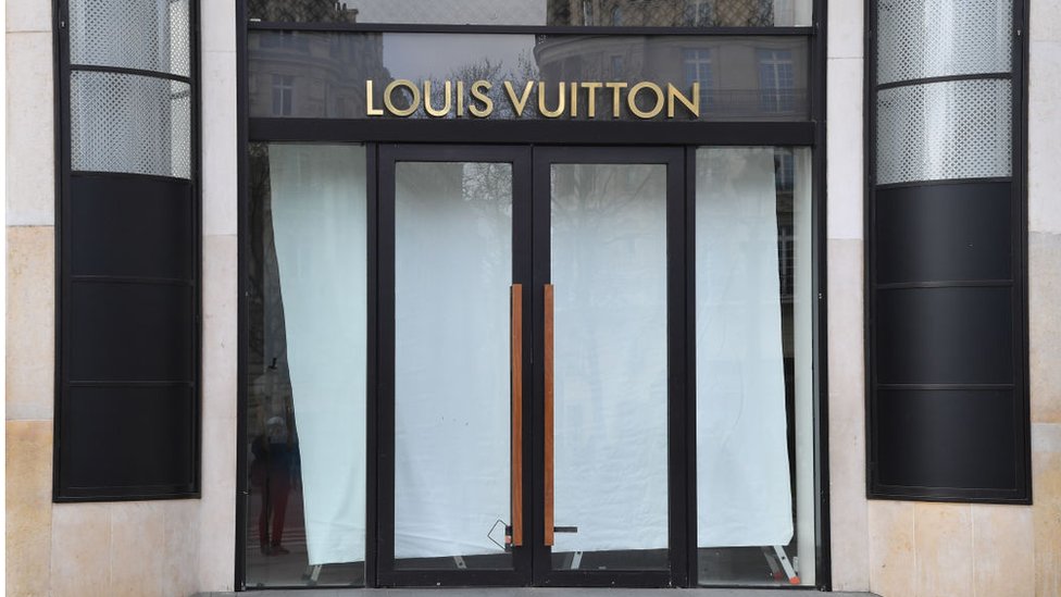 Staff stand at the entrance to a new Louis Vuitton store in