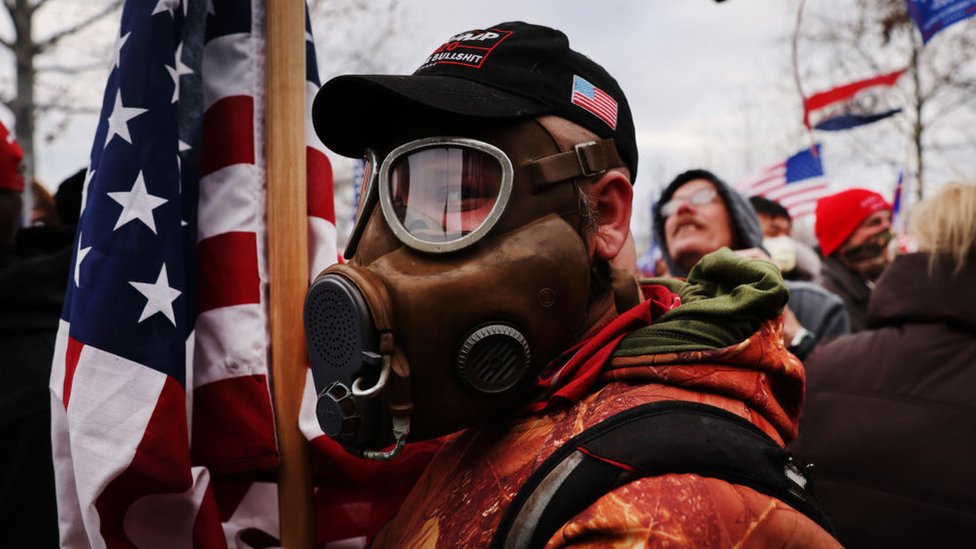 Pendukung Trump terlihat mengenakan masker gas yang memegang bendera AS