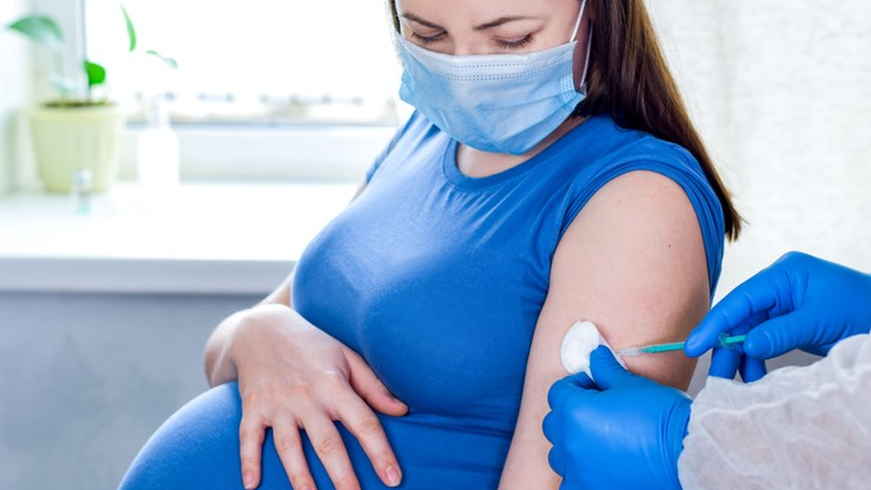 Gestante usando máscara recebe vacina no braço