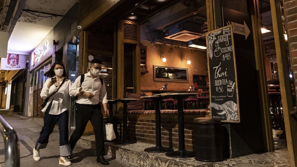 People wearing face masks as a precaution against the spread of Coronavirus walk past an empty restaurant in SoHo area during happy hour. Chief Executive of Hong Kong Carrie Lam announced today, March 23rd, 2020