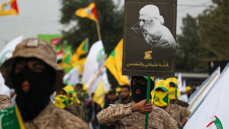 Kataib Hezbollah militia fighters hold up a poster showing Qasem Soleimani and Abu Mahdi al-Muhandis at their funeral in Baghdad (4 January 2019_