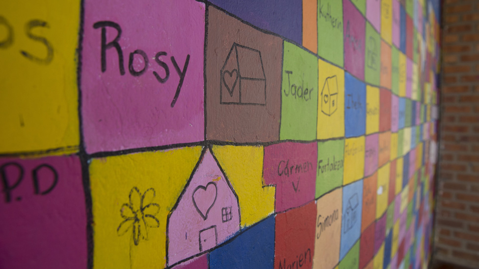 Имена членов Лиги перемещенных женщин и рисунки домов написаны на разноцветной стене общественного центра города.