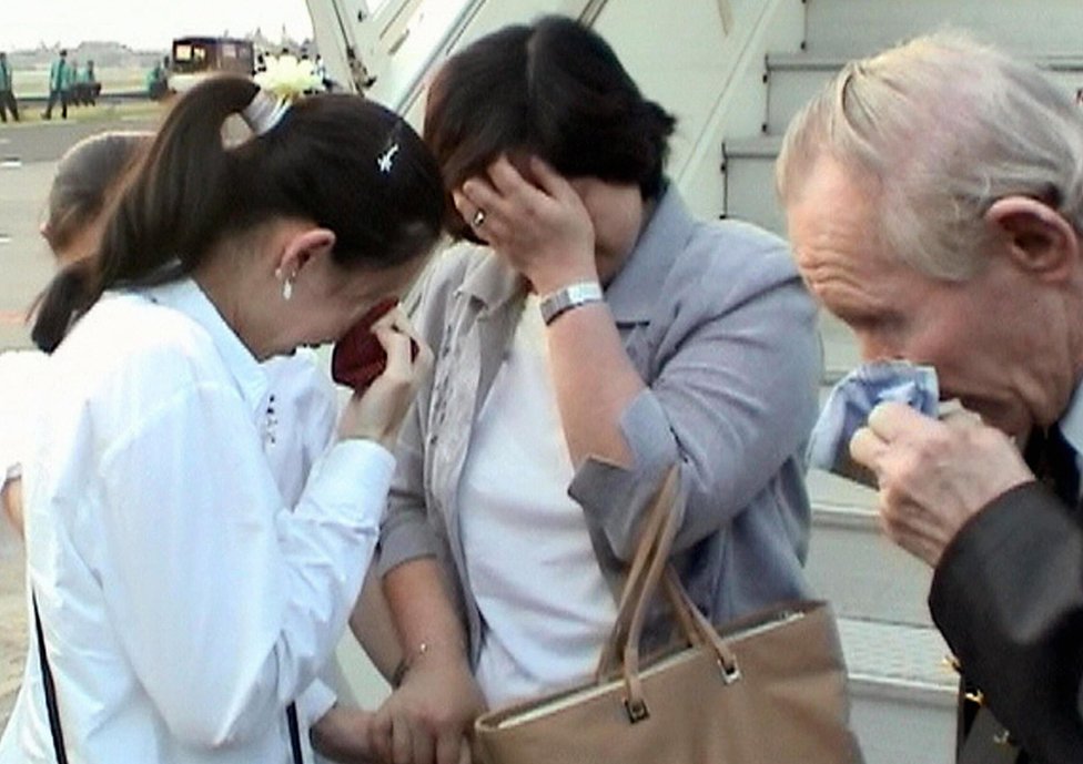 Хитоми Сога, Чарльз Дженкинс и их дочь Мика вытирают слезы, когда они воссоединяются в аэропорту Джакарты 9 июля 2004 года.
