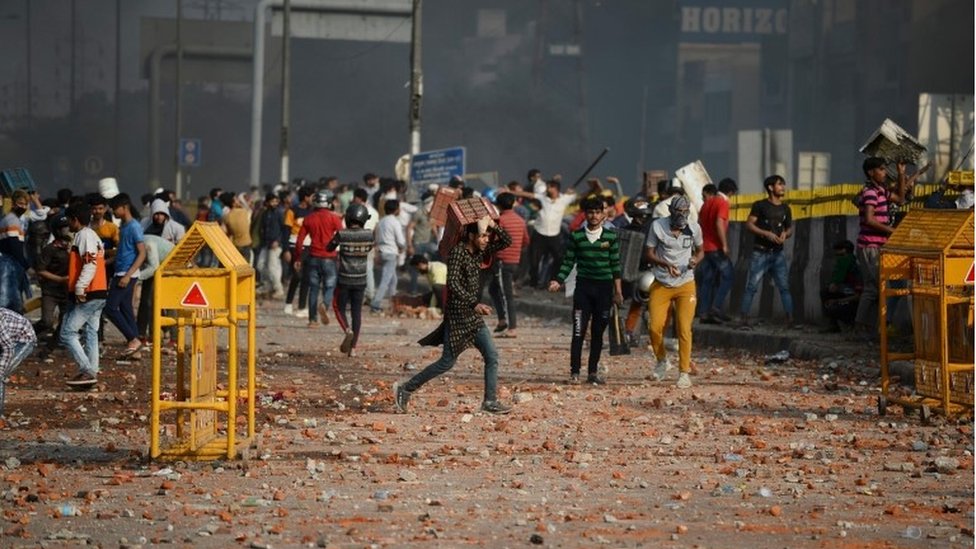 Демонстранты собираются вдоль дороги разбросанные камнями после столкновений между сторонниками и противниками нового закона о гражданстве, в районе Бхаджанпура в Нью-Дели 24 февраля 2020 г. в соответствии с законом Индии о гражданстве в Нью-Дели 26 февраля 2020 г.
