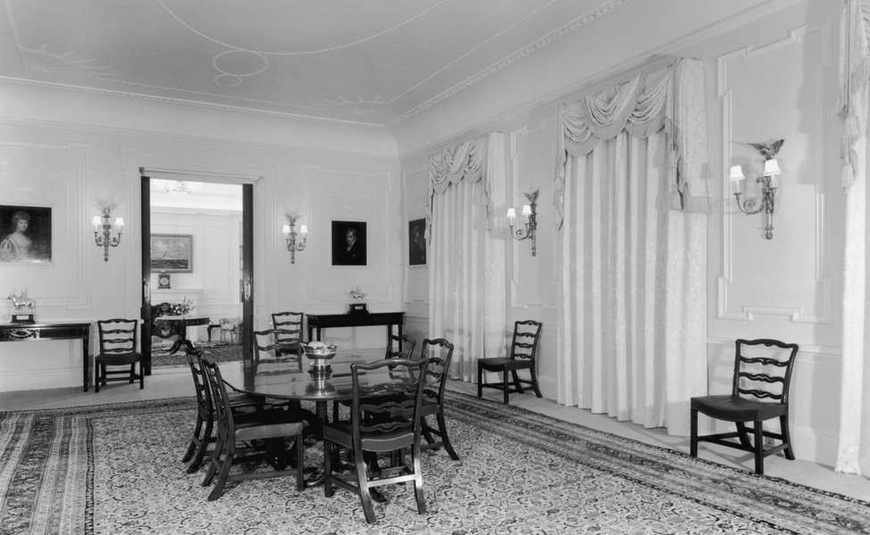 The dining room of Clarence House in London, 1949. The house was built in 1825-27 by John Nash for the Duke of Clarence, later King William IV. The dining table and chairs are mahogany and the curtains are white figured damask