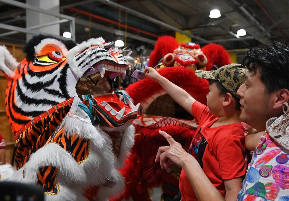 在澳大利亞悉尼唐人街帕迪市場農曆新年慶祝活動現場，一個孩子在舞獅隊表演後，將一張鈔票放入裝扮成「虎年」老虎的嘴裏。