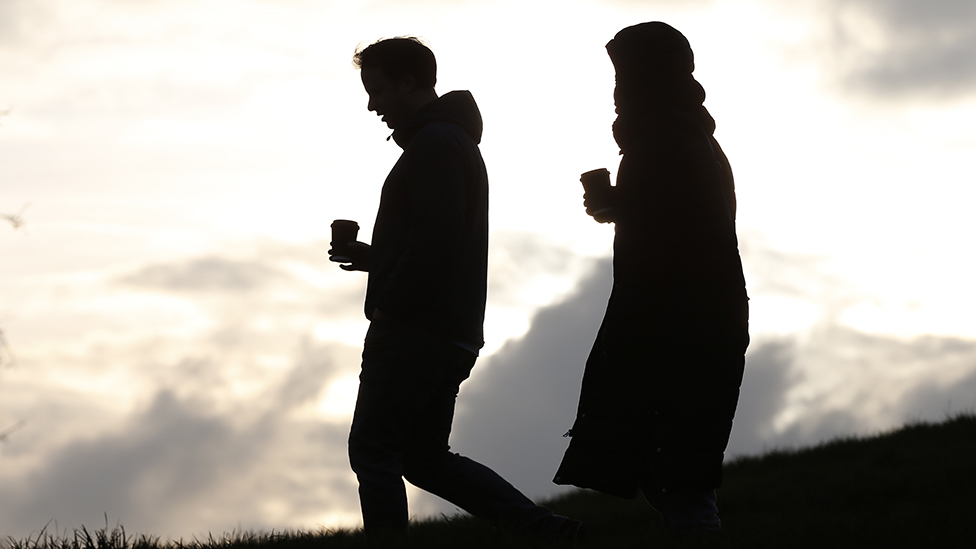 Man and woman in silhouette, walking down hillside