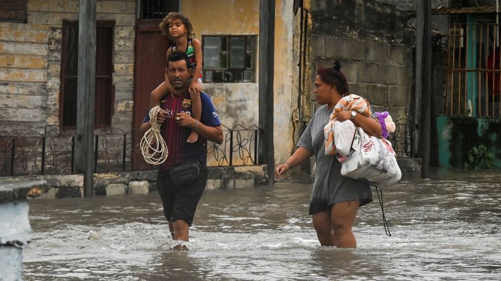 família caminha em meio a alagamento