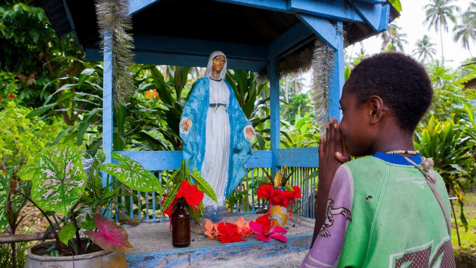 Una joven reza una efigie de la Virgen