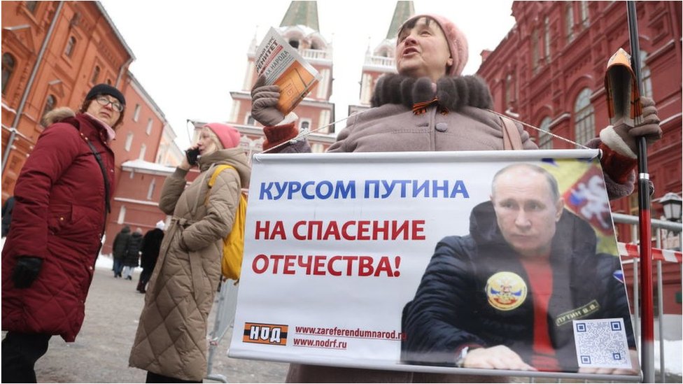 2024年大選前夕，一名婦女在紅場舉著海報，表達她對普京的支持。