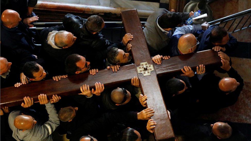 Worshippers carry a large wooden cross into a church in Jerusalem