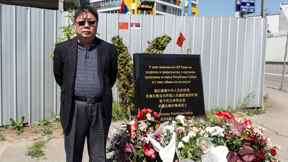 Shen Hong frente a un memorial.