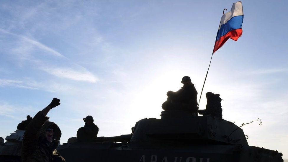 A Russian flag flies near Pro-Russia militants sitting atop a 2S1 Gvozdika (122-mm self-propelled howitzer) as a convoy of pro-Russian forces takes a break as they move from the frontline near the eastern Ukrainian city of Starobeshevo in Donetsk region, on February 25, 2015.