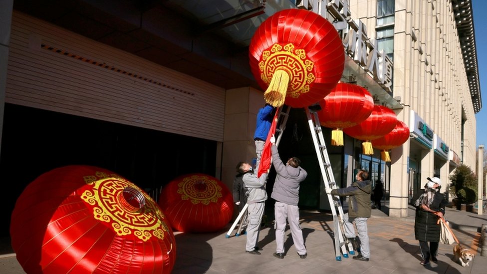 Men hang red lanterns marking New Year and Lunar New Year festivities following the outbreak of Covid-19 in Beijing, 31 December 2020