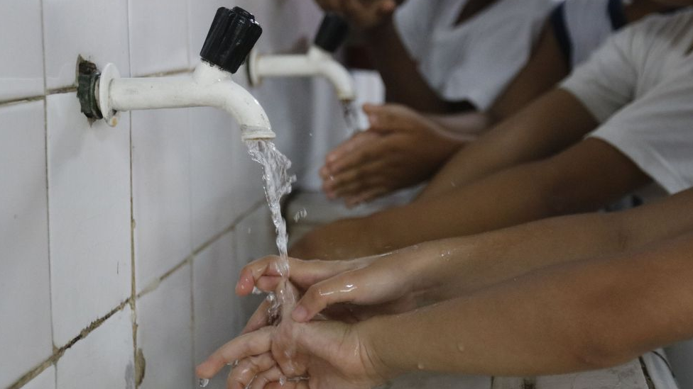 Crianças lavando as mãos em escola, em foto de março