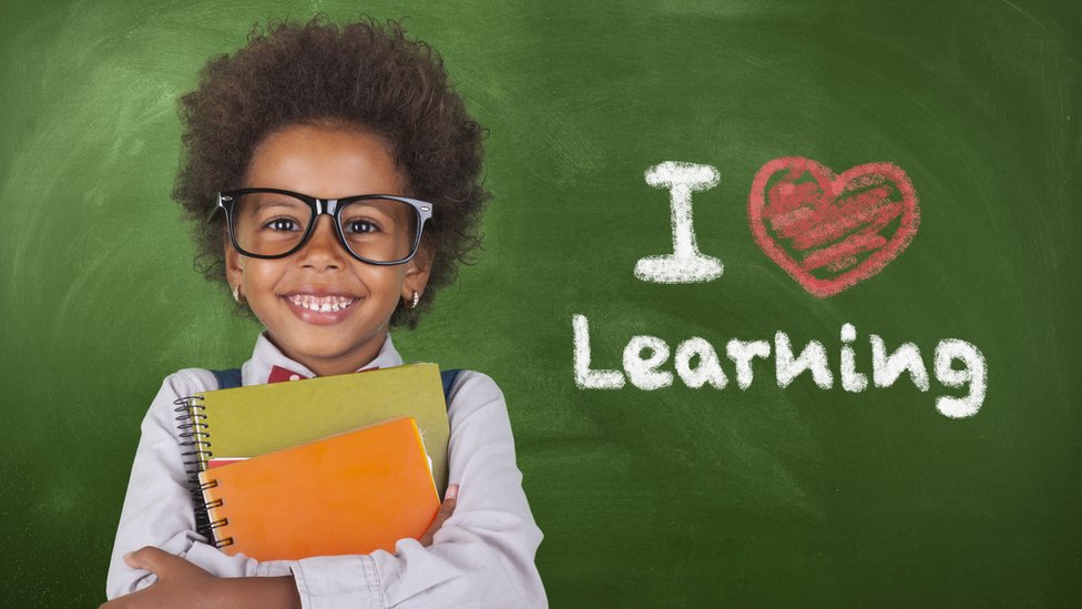 Una niña junto a un letrero que dice "I Love learning"