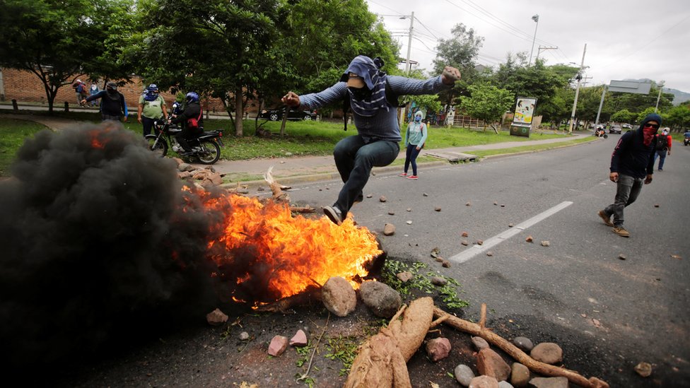 Демонстрант прыгает на баррикаду во время акции протеста против правительства президента Гондураса Хуана Орландо Эрнандеса в Тегусигальпе