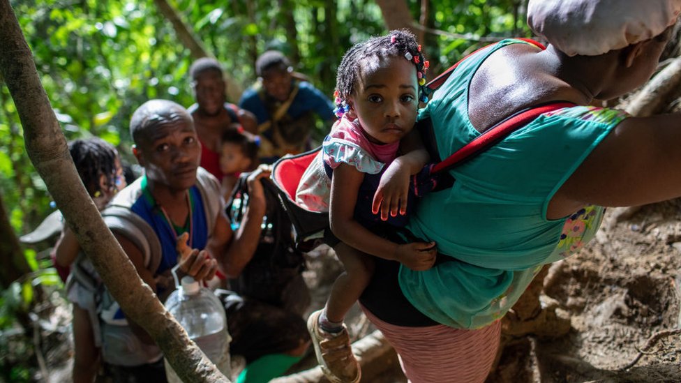 Famílias de imigrantes do Haiti escalam uma trilha de montanha íngreme perto da fronteira com o Panamá no segundo dia de sua jornada em 19 de outubro de 2021 pelo Darien Gap, Colômbia.