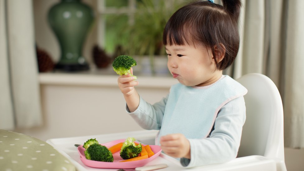 A girl eating broccoli