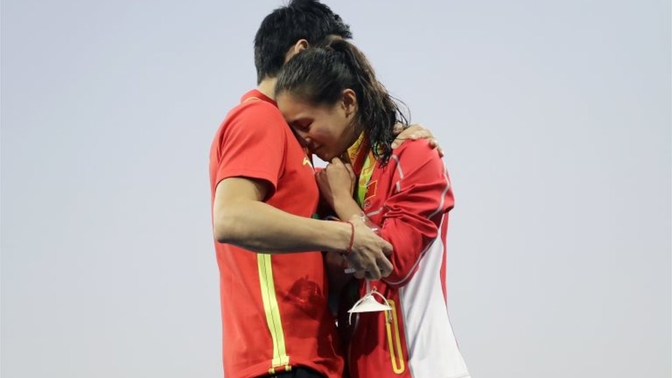 Китайский ныряльщик Цинь Кай (слева) делает предложение серебряному призеру Хэ Чжи в финале соревнований по прыжкам в воду с 3-метрового трамплина среди женщин в водном центре Марии Ленк на летних Олимпийских играх 2016 года в Рио-де-Жанейро, Бразилия, воскресенье, 14 августа. 2016.