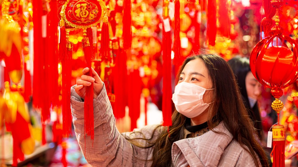 Una joven mira decoraciones de Año Nuevo en una tienda en China