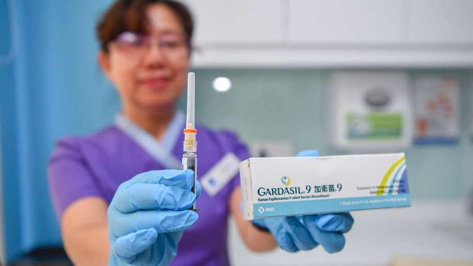 A doctor in China holding the Gardasil box