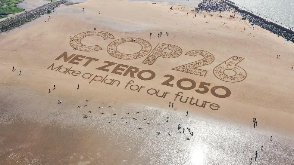 Imagen grababa en la arena en una playa en Inglaterra que dice "COP 26, cer oneto para 2050, hagan un plan para nuestro futuro".
