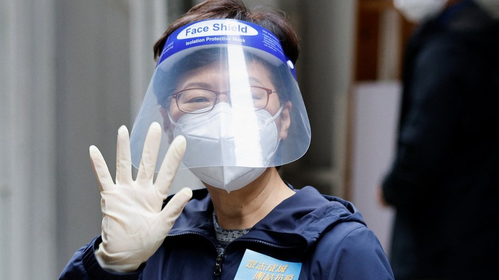 Hong Kong Chief Executive Carrie Lam, wearing a face mask and a shield, waves to the media after delivering anti-epidemic service bags to residents during the coronavirus disease (COVID-19) pandemic, in Hong Kong, China, April 2, 2022.
