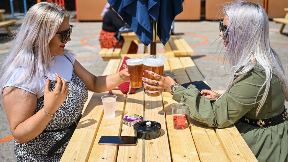 Two women with pints of beer sitting in a pub garden