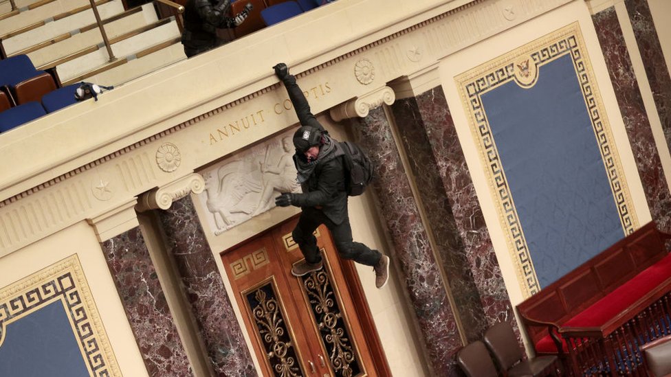 A protester hangs from the wall of the US Senate chamber