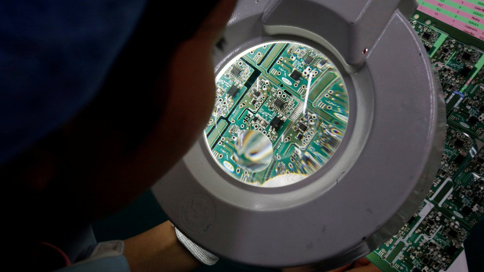 A woman looks through a magnifying glass to check errors of a printer circuit board at Manutronics Factory in Bac Ninh province, Vietnam May 30, 2018.