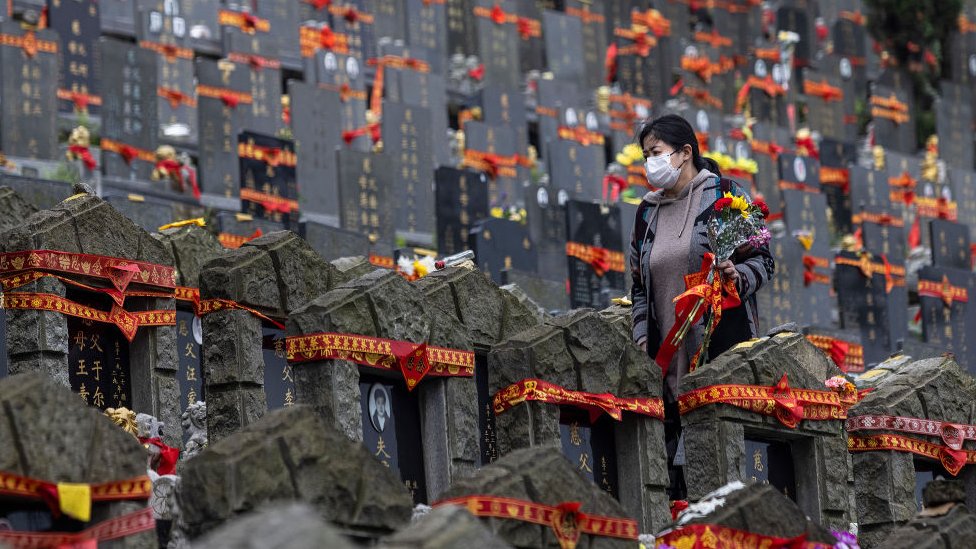 A woman wearing a mask while sweeping tombs in Wuhan