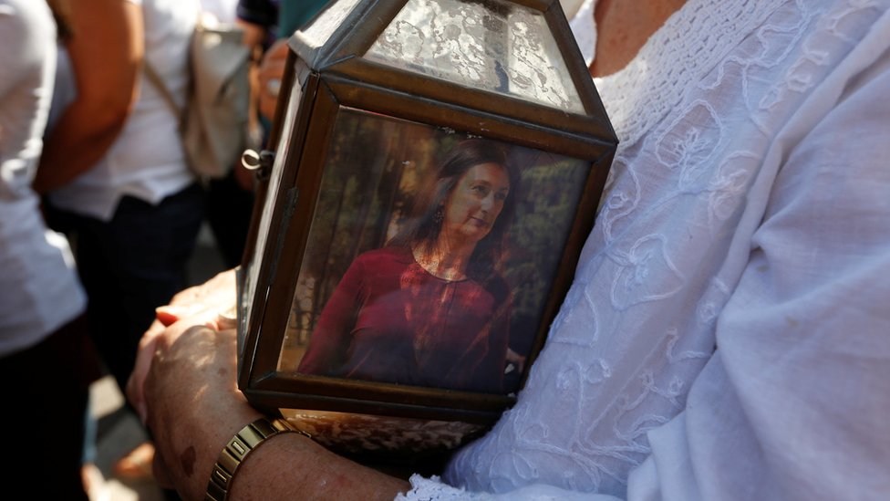 Женщина держит фонарь с фотографией журналиста-расследователя Дафны Каруаны Галиции, убитой в результате взрыва заминированного автомобиля во время акции протеста у здания судов в Валлетте, Мальта, 17 октября 2017 г.