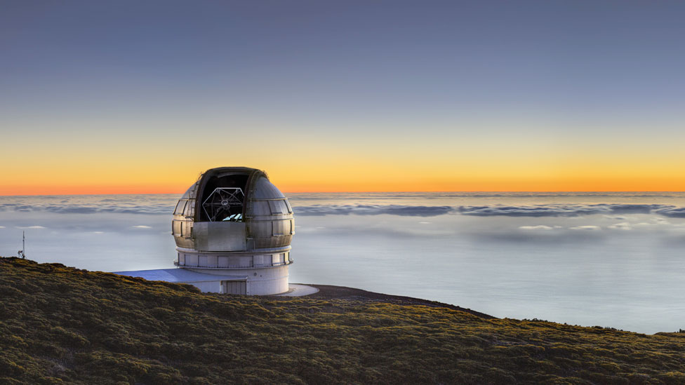 Gran Telescopio Canaria sobre un horizonte de nubes iluminadas por el Sol