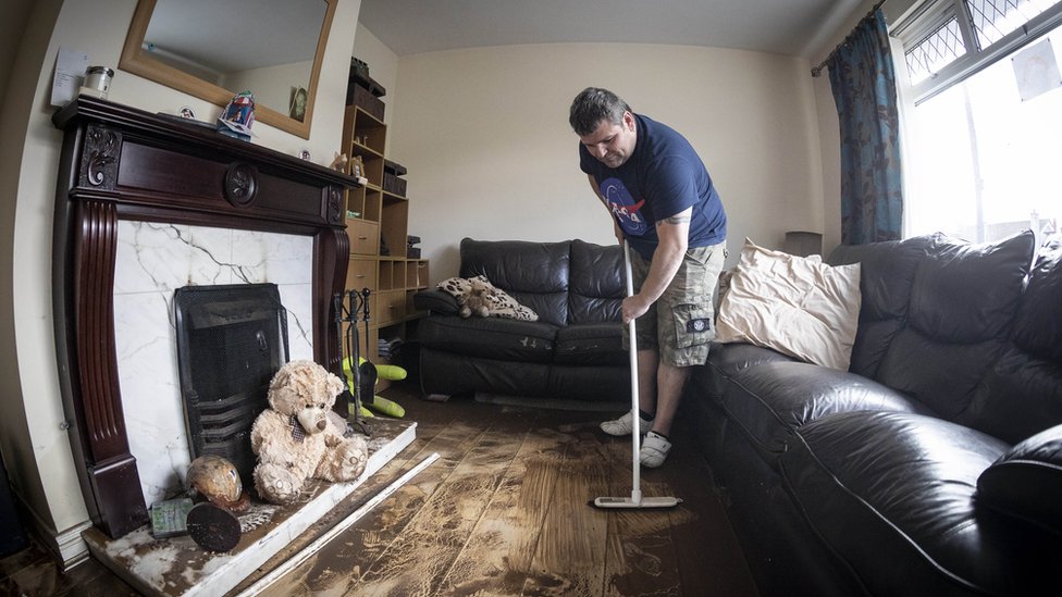 Житель убирает свой дом после наводнения в Ньюкасле
