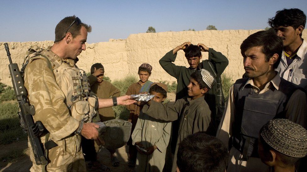 مترجم أفغاني بصحبة القوات البريطانية يتحدث إلى أطفال أفغان.