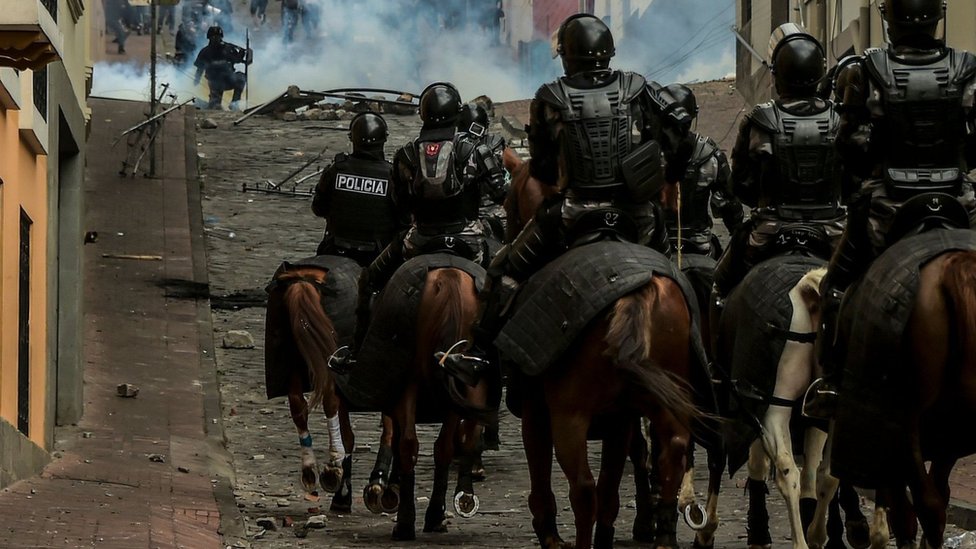 Около 10 полицейских на лошадях маршируют по холмистым улицам Кито