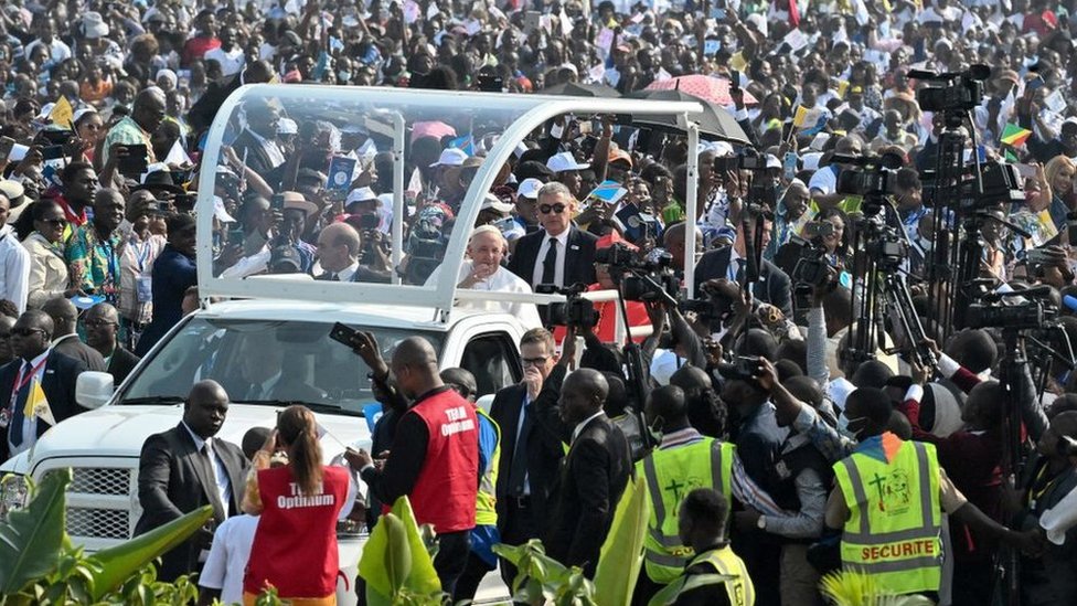 Pope in vehicle surrounding my hundreds of people