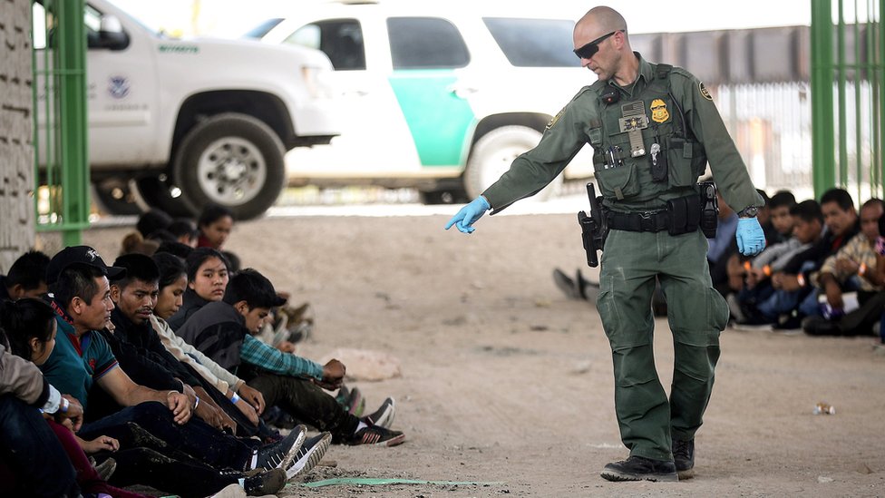 Un agente de la Patrulla Fronteriza señala a un grupo de migrantes detenidos en la frontera entre EE.UU. y México.