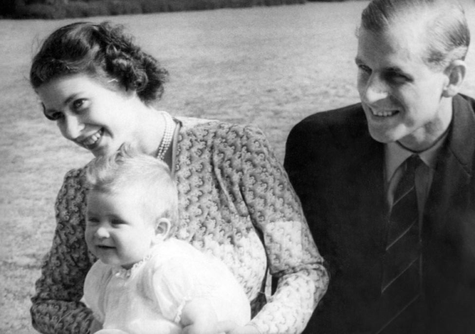 La princesa Isabel de Inglaterra y su esposo, el príncipe Felipe, duque de Edimburgo, con el bebé Carlos en julio de 1949 en Windlesham Moor, Surrey.