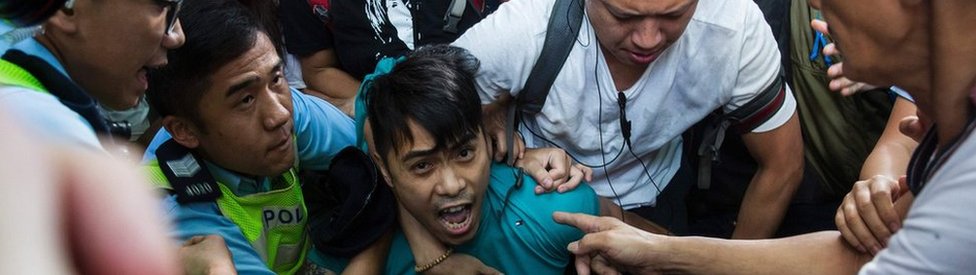 Сторонник Пекина принудительно удален полицией, когда он пытается остановить протест Лиги социал-демократов в Гонконге, 1 июля 2017 г.