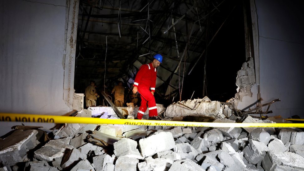 An emergency worker picks through rubble at the remains of the site where the wedding celebration took place