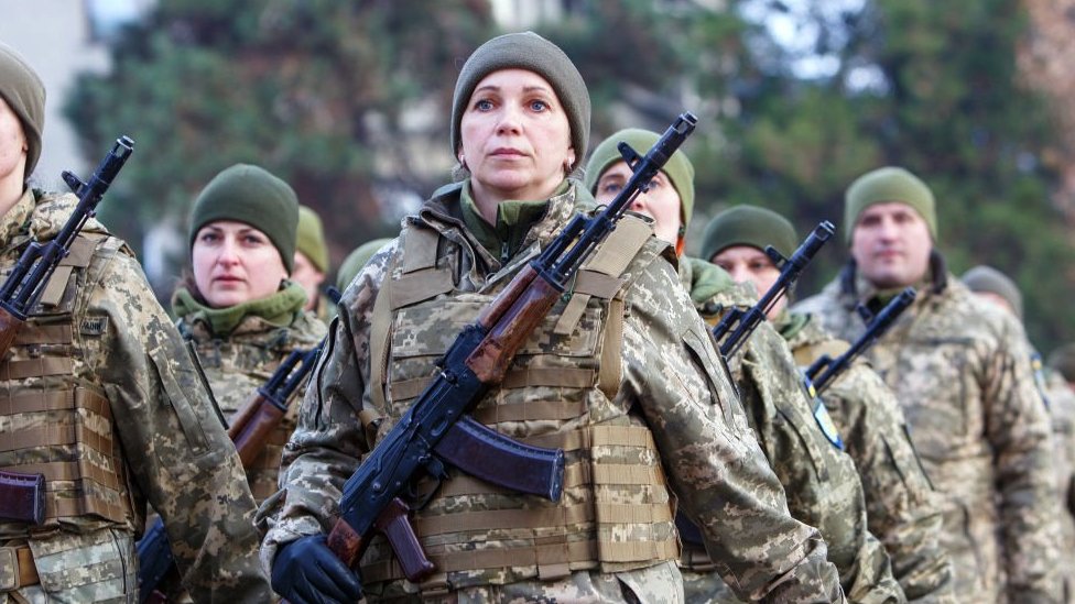 A Ukrainian woman in uniform is seen at a drill with other soldiers