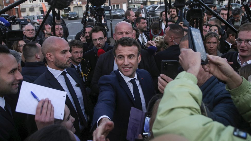 Emmanuel Macron in a crowd of people and cameras