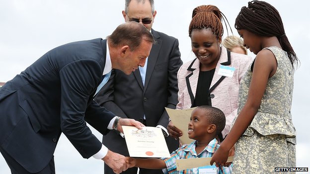 Премьер-министр Тони Эбботт вручает сертификаты семье Тарувинга из Зимбабве на церемонии получения гражданства 26 января 2015 года в Канберре, Австралия