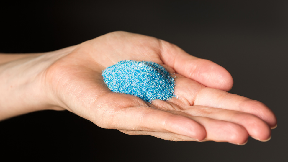 Microplásticos extraídos de productos de belleza en la palma de una mano